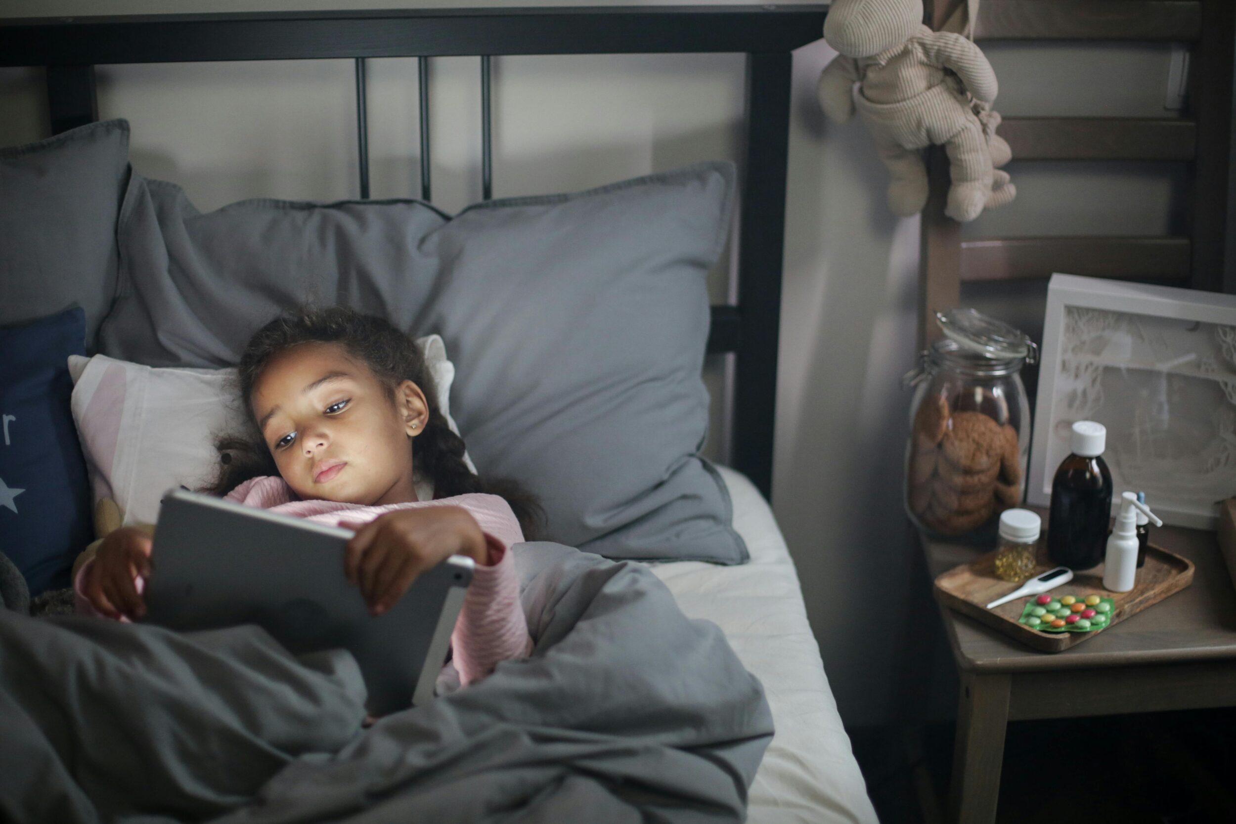 Young child using a tablet in bed, illustrating screen time for children and the importance of healthy screen time guidelines.