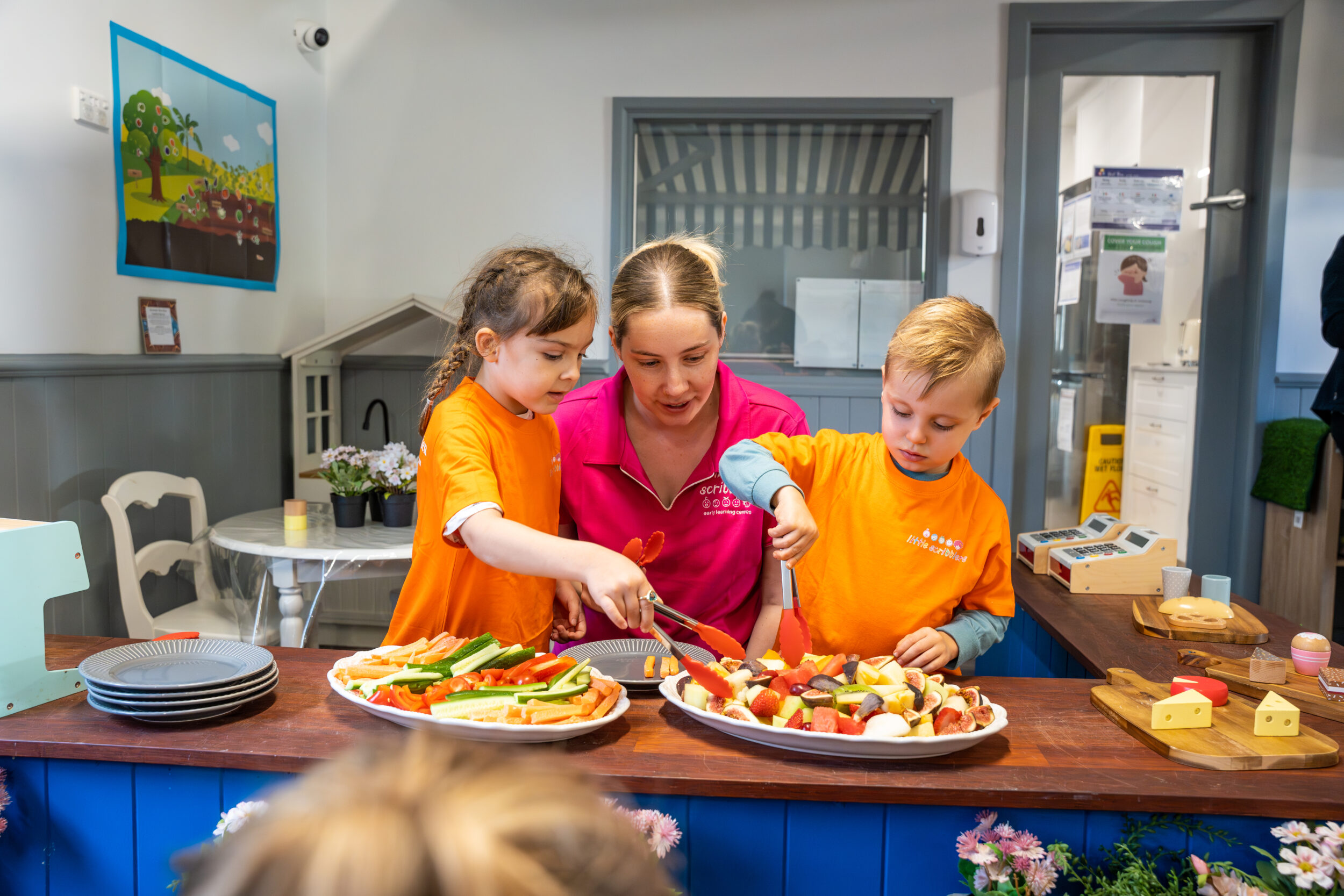 2 preschoolers with educator during organised snack time with fresh fruit at our Early Learning Centre