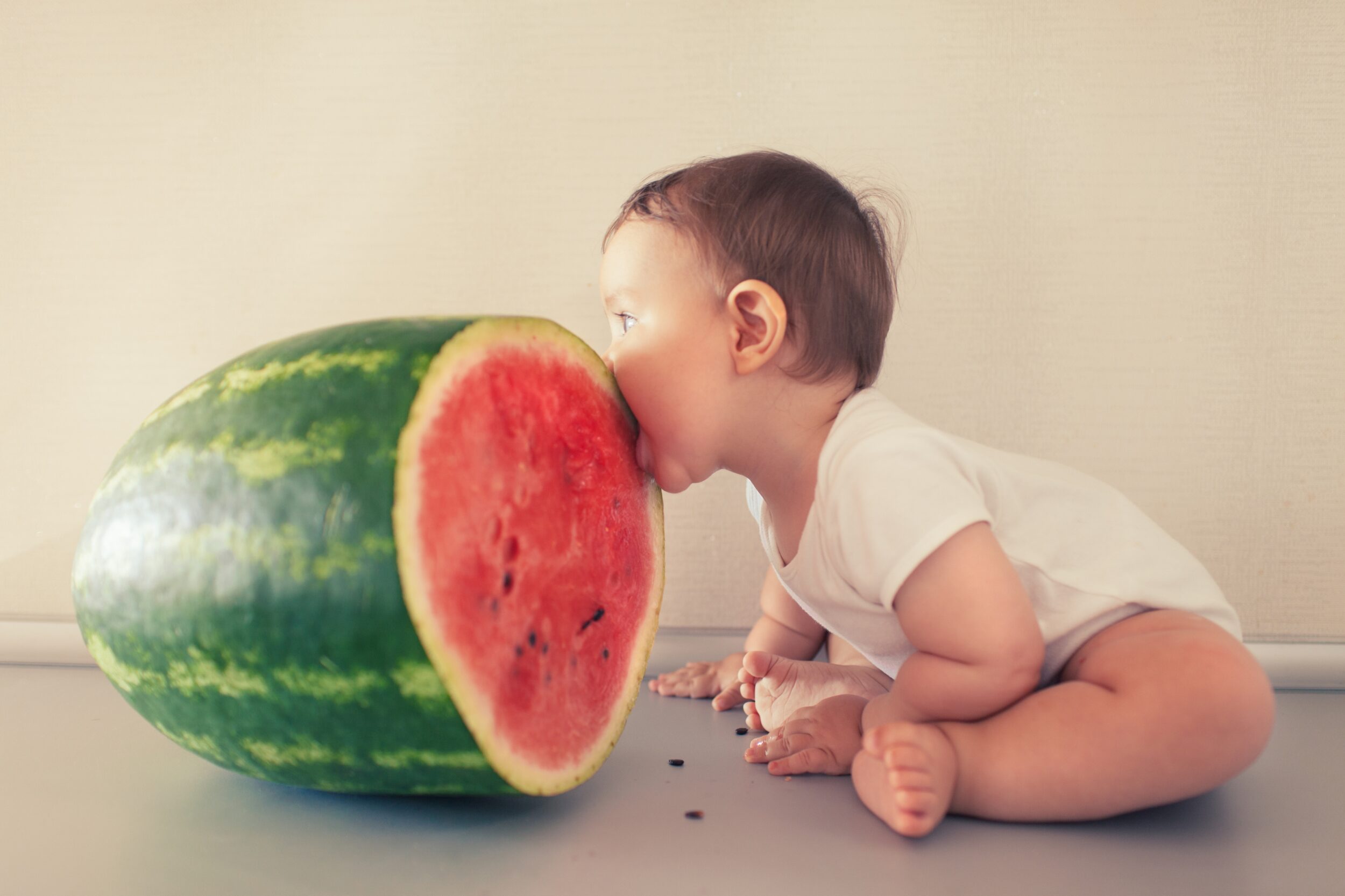 : A baby playfully biting a large watermelon slice, illustrating the concept of young children exploring through biting — “Oh My Goodness! I Just Found Out My Child Is a Biter – What Now?”