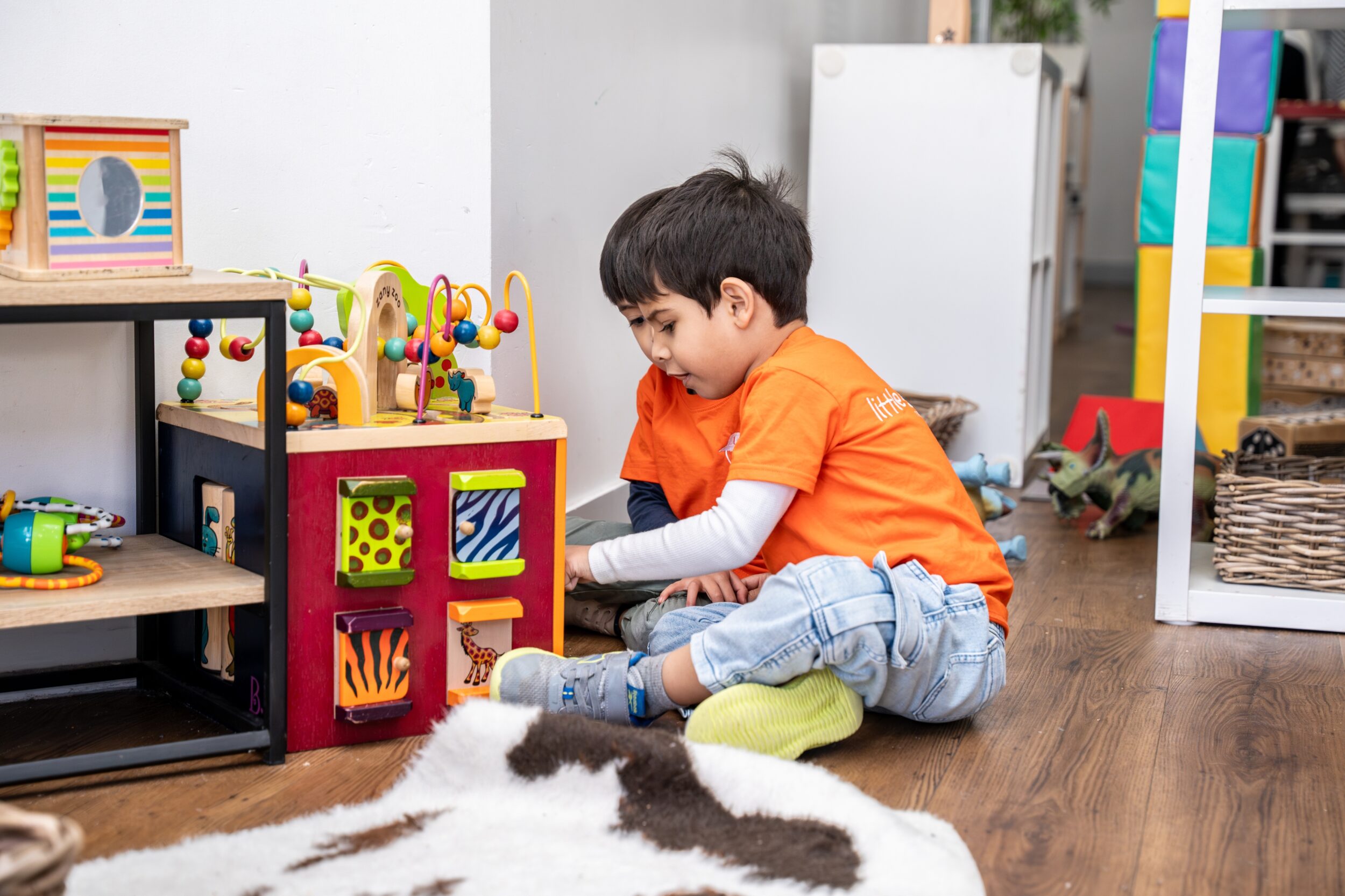 Child engaging in hands-on play-based learning with a wooden problem-solving cube at Little Scribblers, illustrating the benefits of early childhood education.